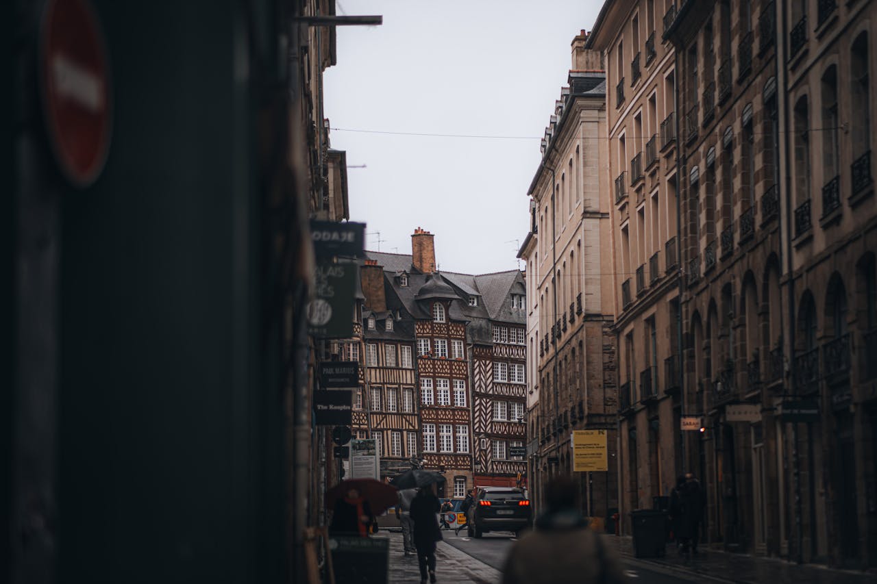 A picturesque street view of Rennes, showcasing traditional half-timbered architecture on a cloudy day.