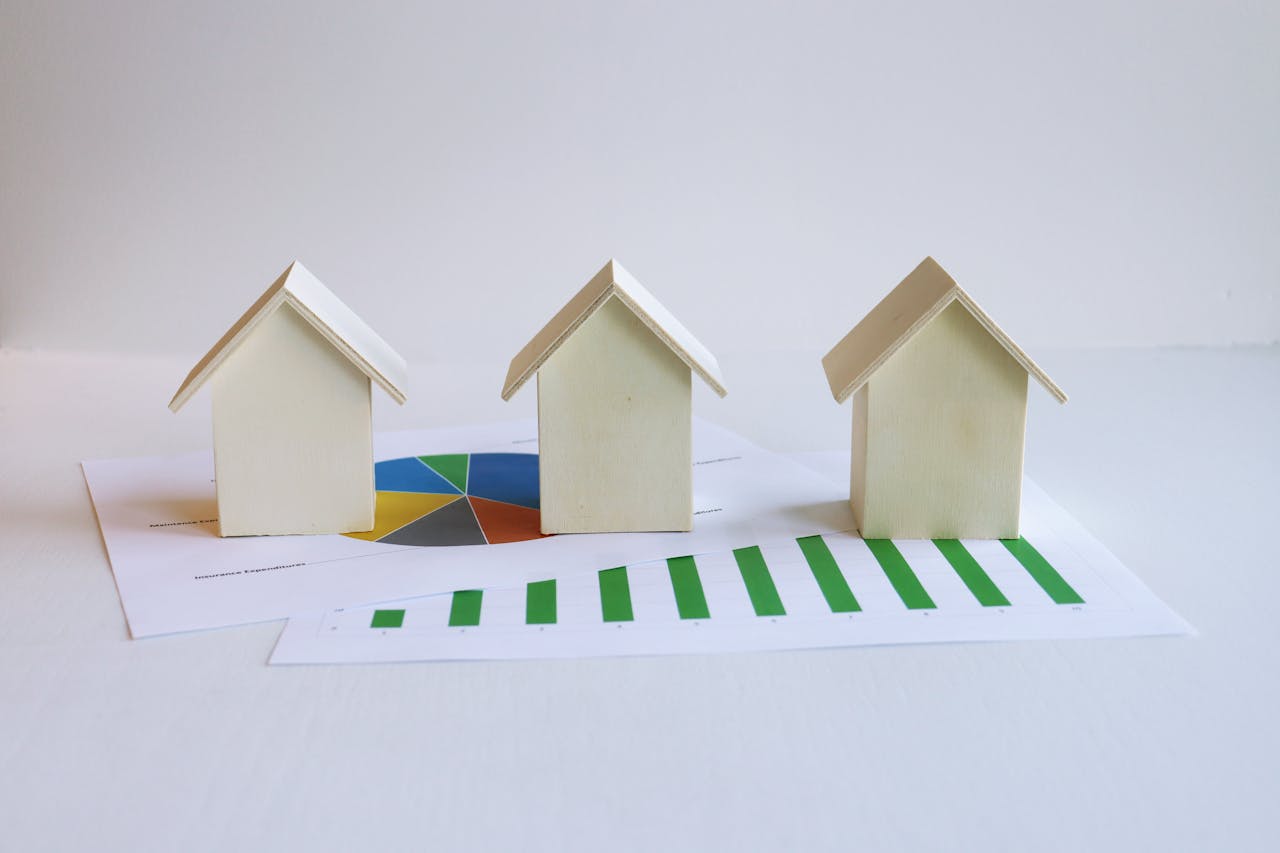 Wooden model houses on graphs depict real estate market analysis and trends.
